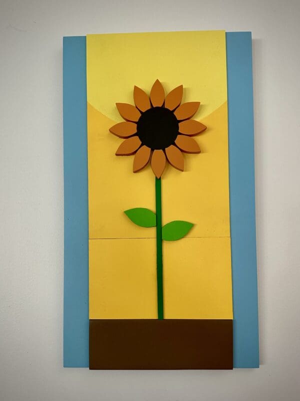 A sunflower made out of wood blocks and paper.