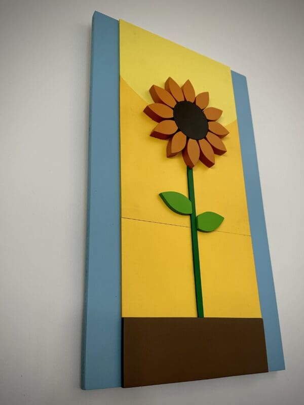 A sunflower in the middle of a blue and yellow wall.